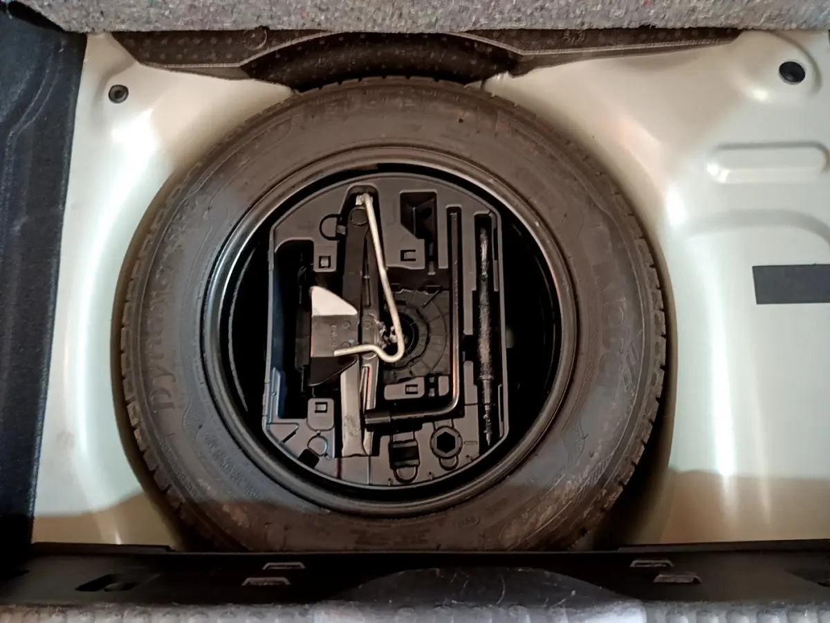 Vue plongeante sur la roue de secours et son rangement dans le coffre d'une Citroën C3 gris clair 2019.