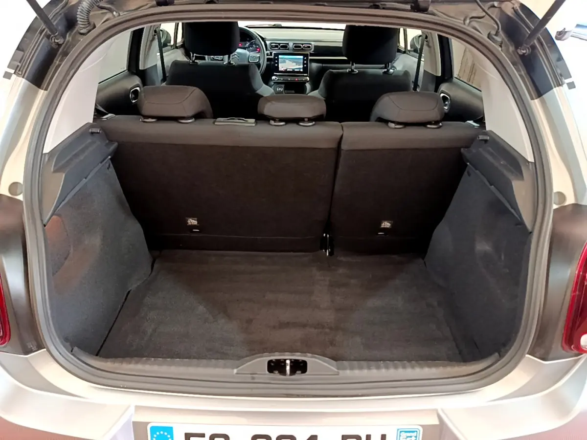 Coffre ouvert vu de l'arrière d'une Citroën C3 gris clair, montrant l'espace de chargement et l'intérieur noir.