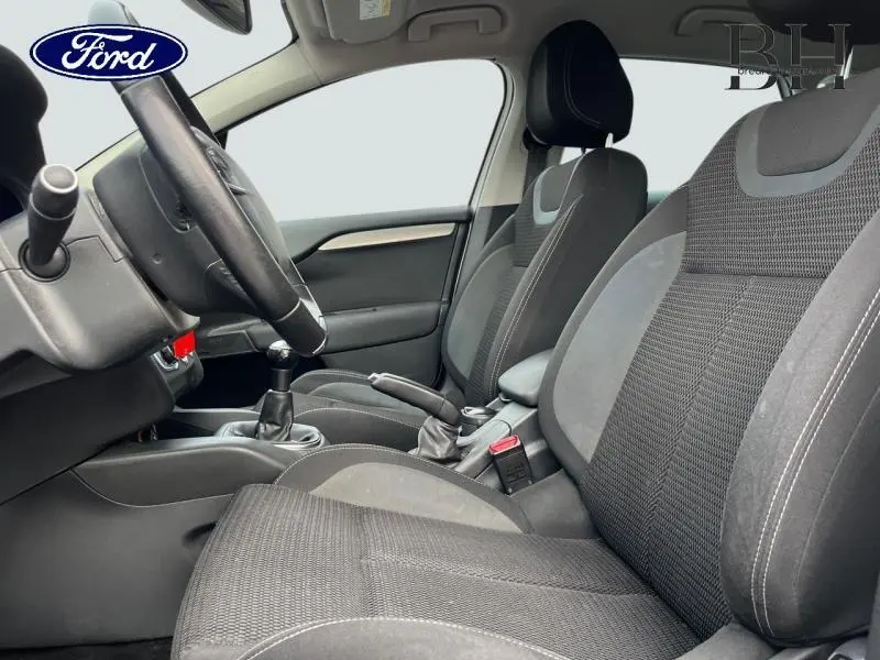 Vue intérieure côté conducteur montrant les sièges avant en tissu gris et la boîte manuelle d'une Citroën C4 blanche.