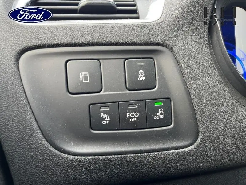 Gros plan sur les boutons de commande noirs du tableau de bord d'une Citroën C4 blanche, avec indicateur vert allumé.