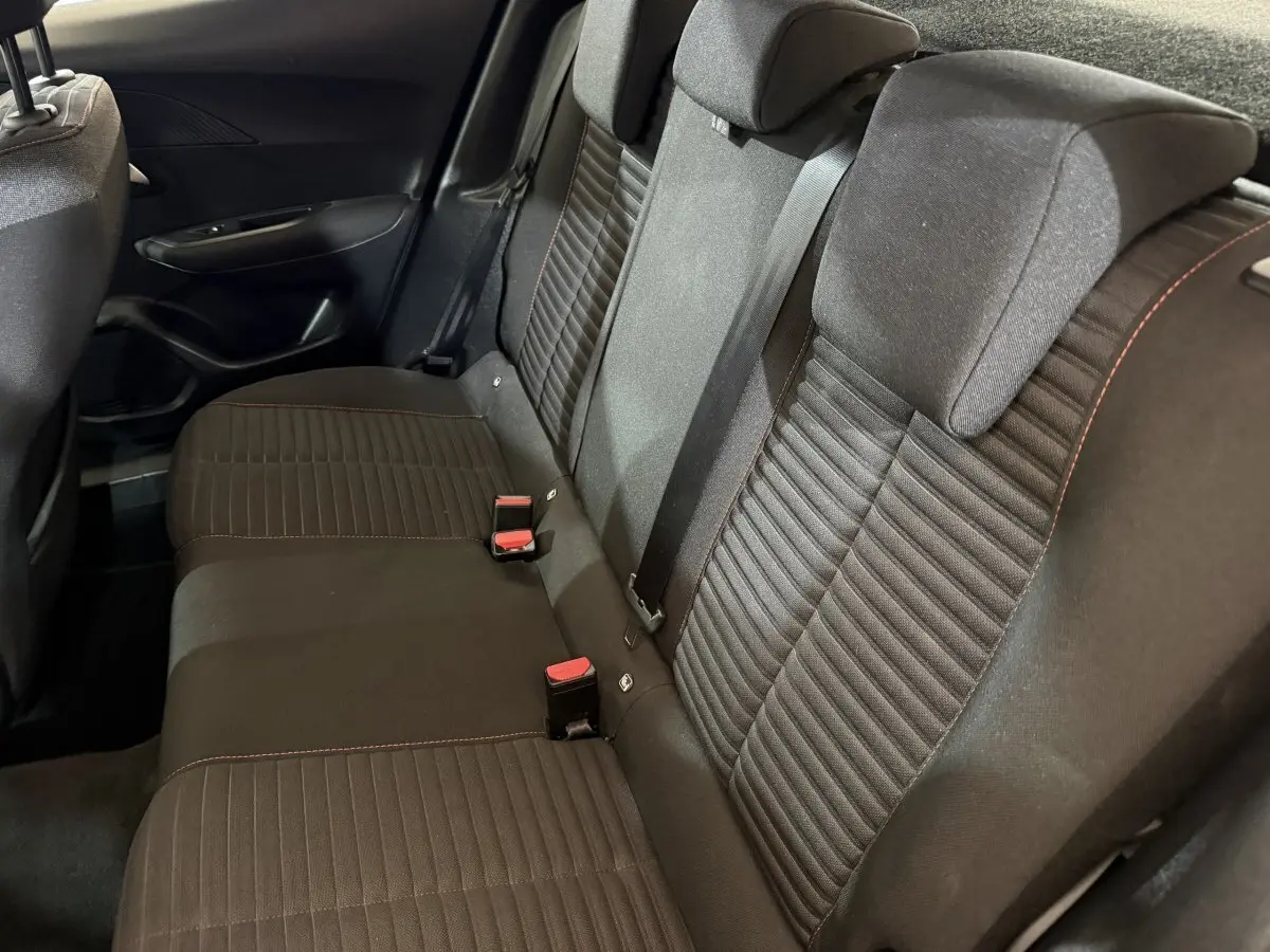 Vue latérale des sièges arrière noirs avec surpiqûres rouges dans le Peugeot 2008 blanc, version Active Business 2021.