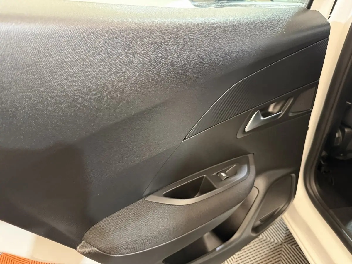 Vue rapprochée de la porte arrière gauche noire du Peugeot 2008 blanc, avec poignée et commande de vitre intégrée.