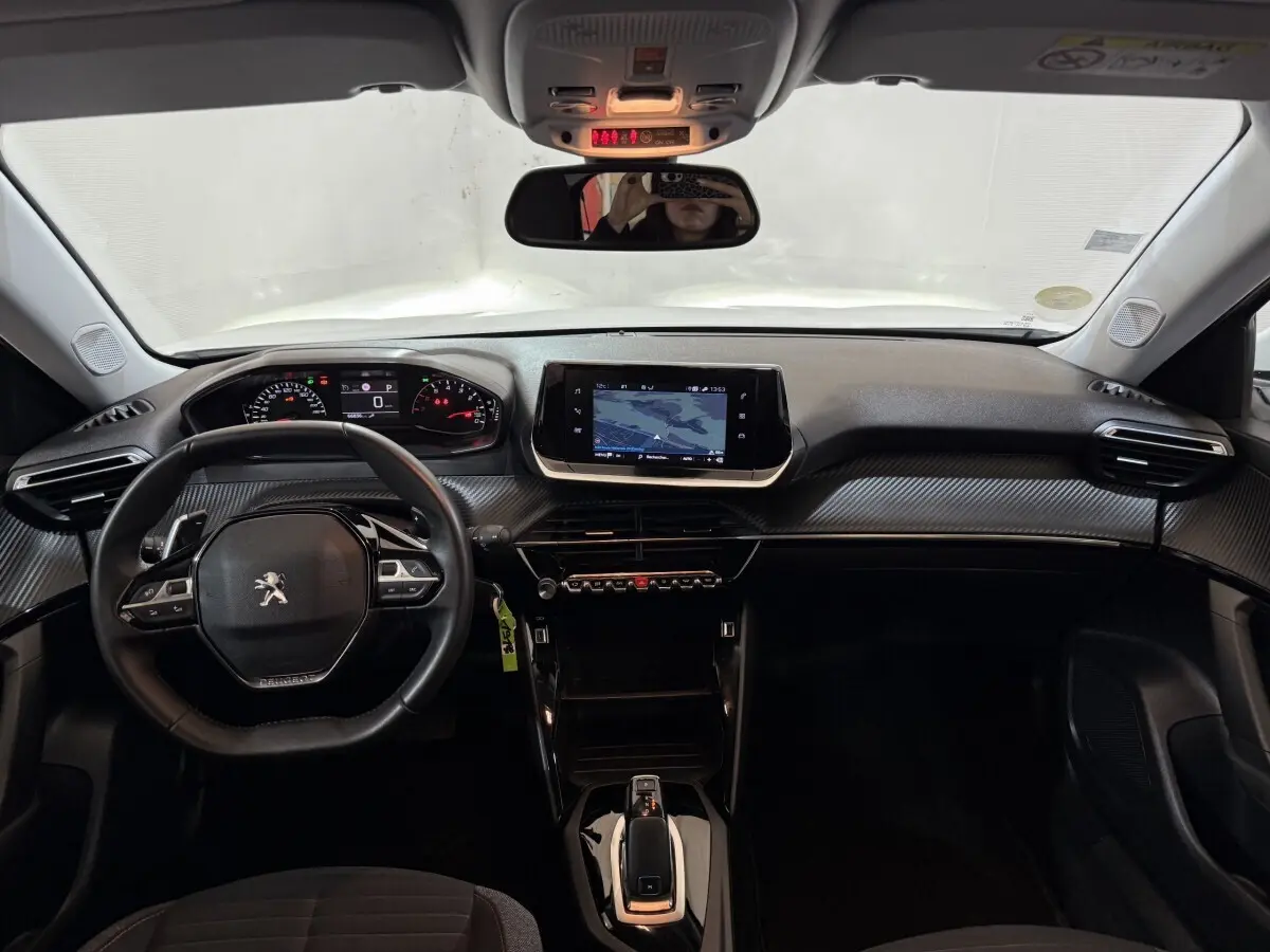 Vue intérieure avant du tableau de bord noir du Peugeot 2008 avec écran tactile central et volant cuir multifonctions.