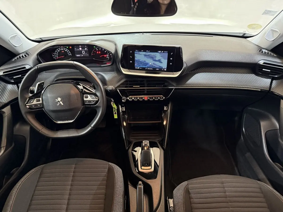 Vue intérieure avant du tableau de bord et volant cuir noir du Peugeot 2008 blanc avec écran tactile central et console moderne.