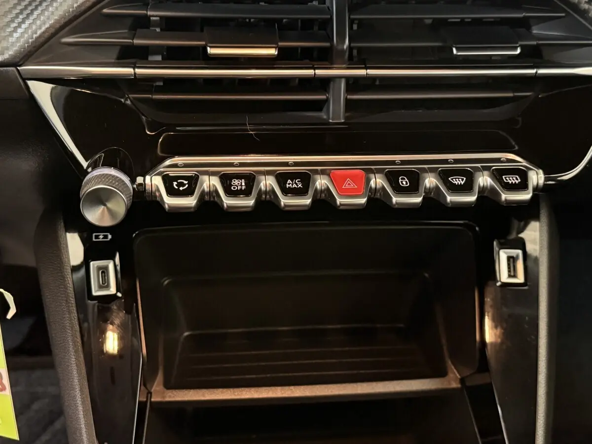 Vue rapprochée de la console centrale noire du Peugeot 2008 avec boutons de commande et ports USB visibles.
