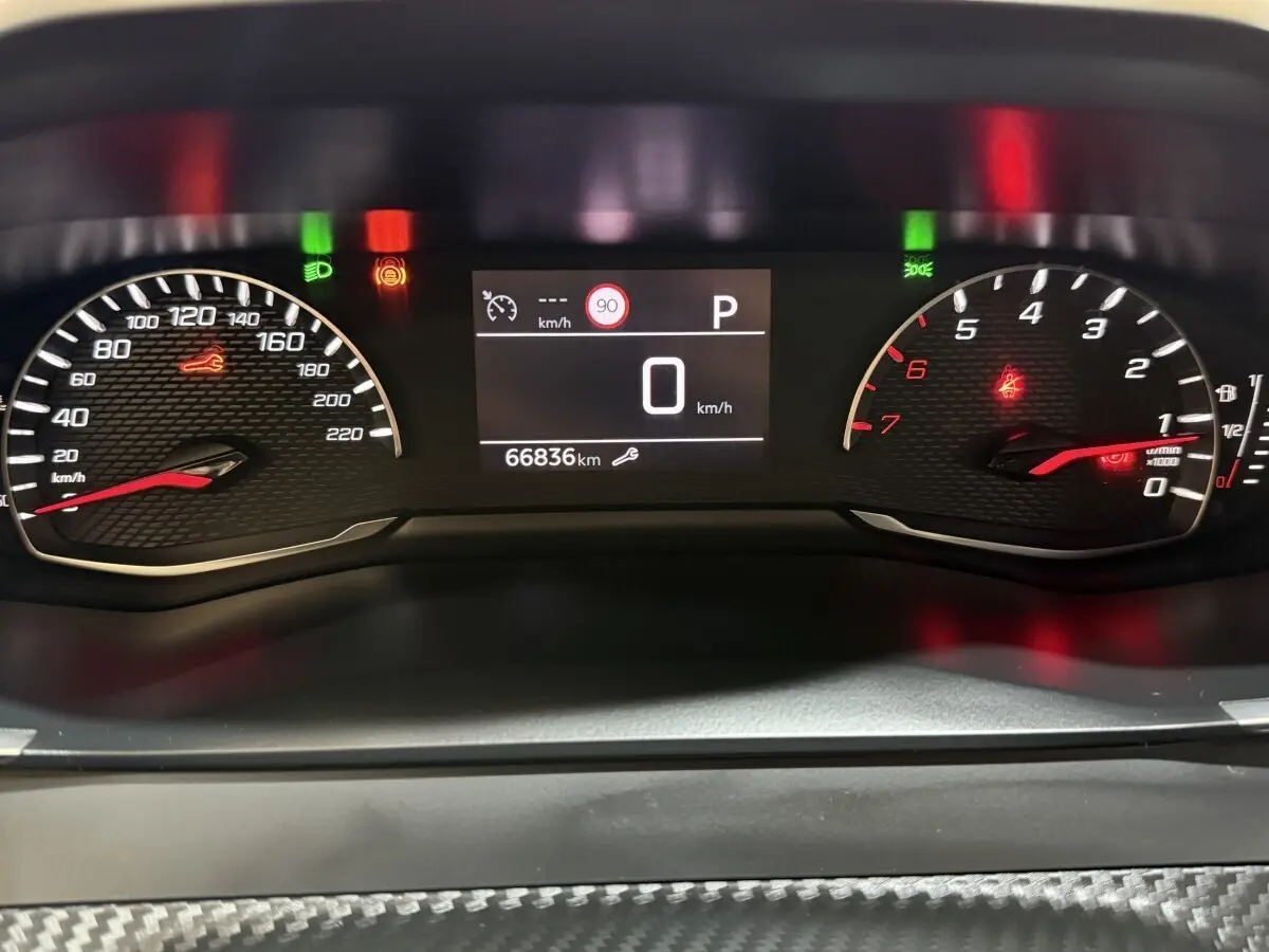 Vue rapprochée du tableau de bord numérique du Peugeot 2008 blanc, affichant 66 836 km et indicateurs allumés.