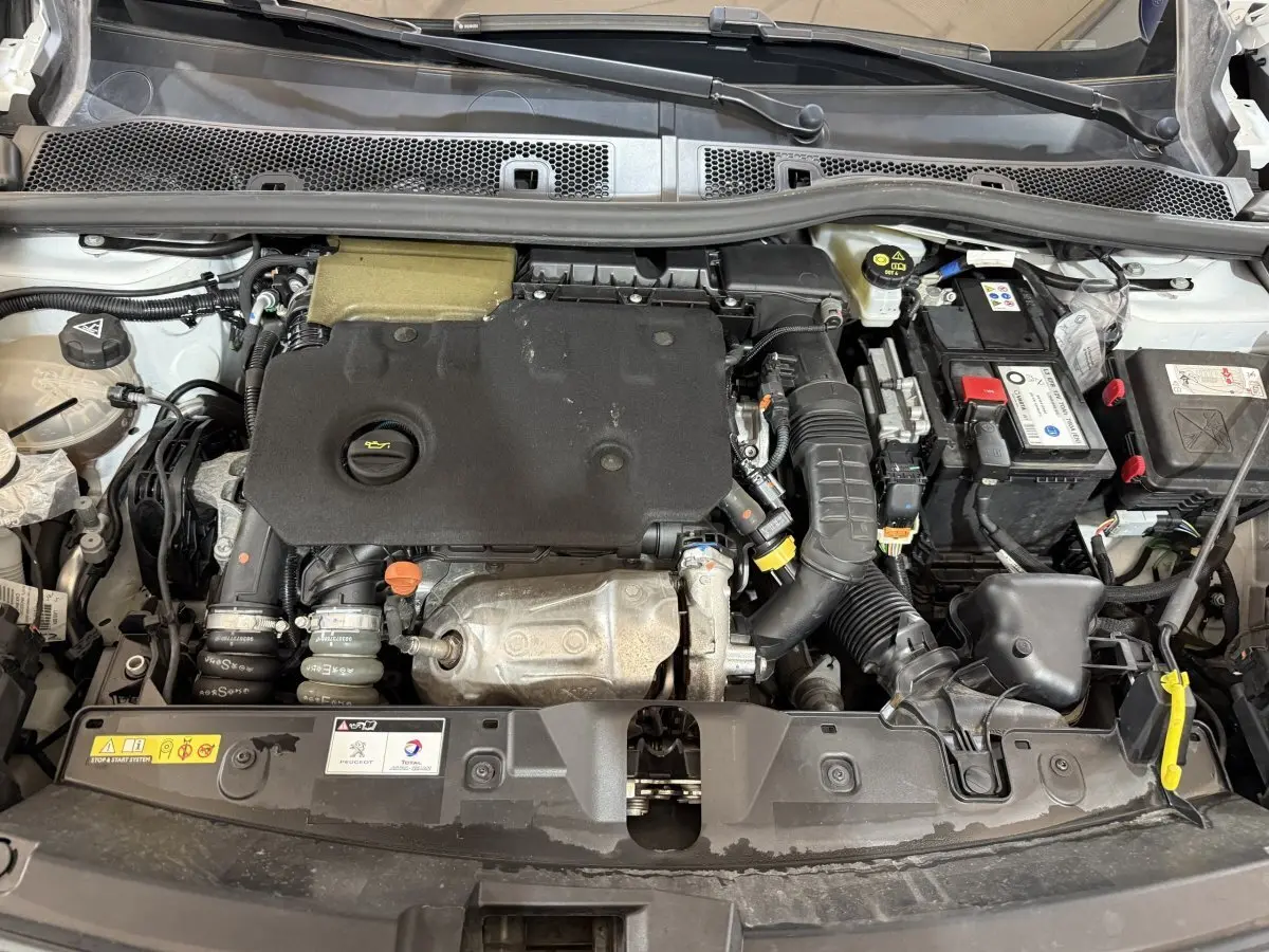 Vue plongeante sur le moteur diesel d'une Peugeot 2008 blanche, version BlueHDi 130 avec capot ouvert.