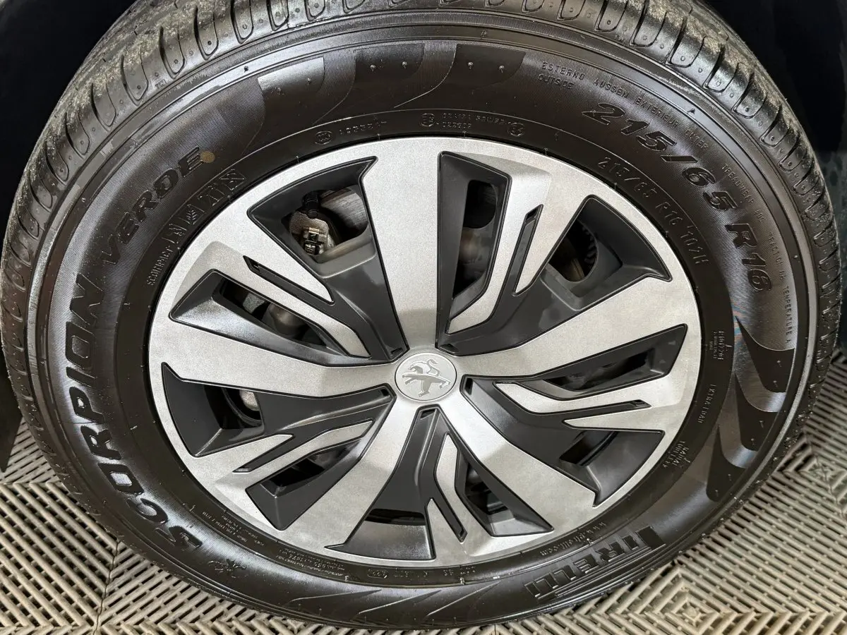 Gros plan sur la jante alliage argent et noir du Peugeot 2008 blanc, mettant en valeur le logo lion central.