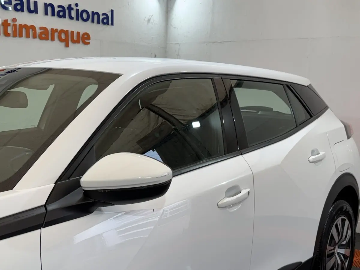 Vue côté gauche rapprochée du Peugeot 2008 blanc, mettant en valeur la porte arrière et le rétroviseur.