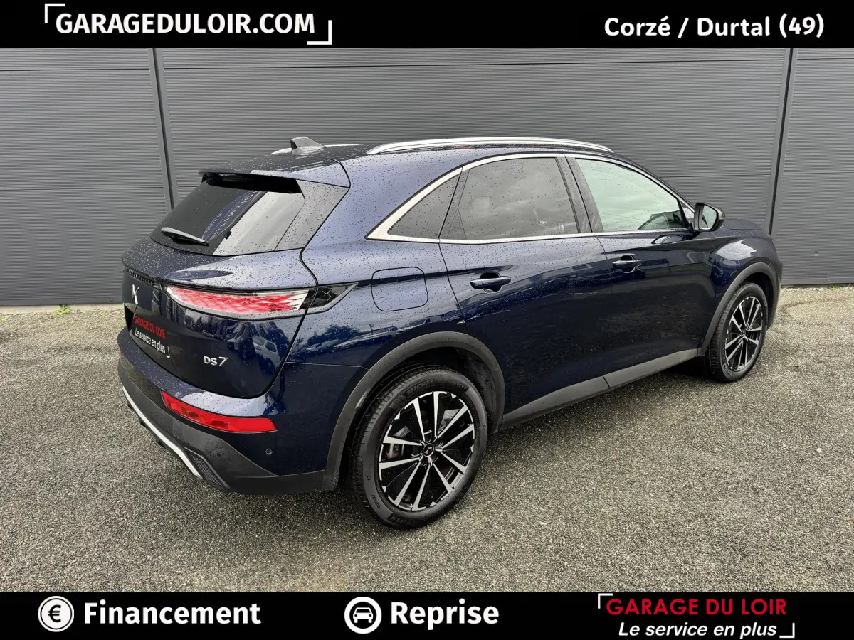 Vue 3/4 arrière droite d’un DS7 Crossback bleu foncé 2024 avec jantes alliage noires et feux arrière LED distinctifs.