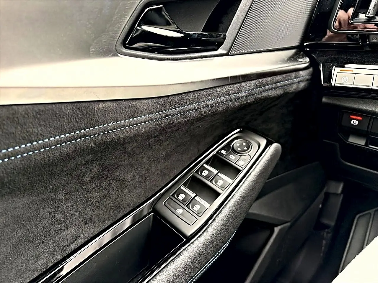 Détail de la porte côté conducteur du Renault Austral gris schiste, avec commandes de vitres et surpiqûres bleues.