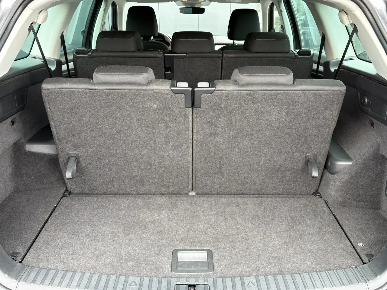 Vue arrière du coffre du Skoda Kodiaq 1.5 TSI gris graphite avec sièges arrière rabattus en position verticale.