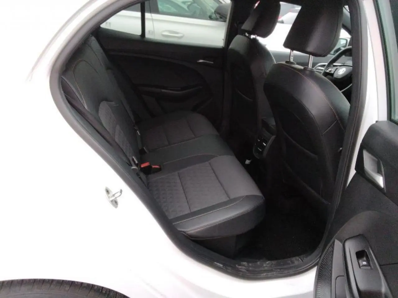 Vue intérieure côté arrière gauche du MG3 blanc Dover, montrant les sièges arrière en tissu et similicuir noir.