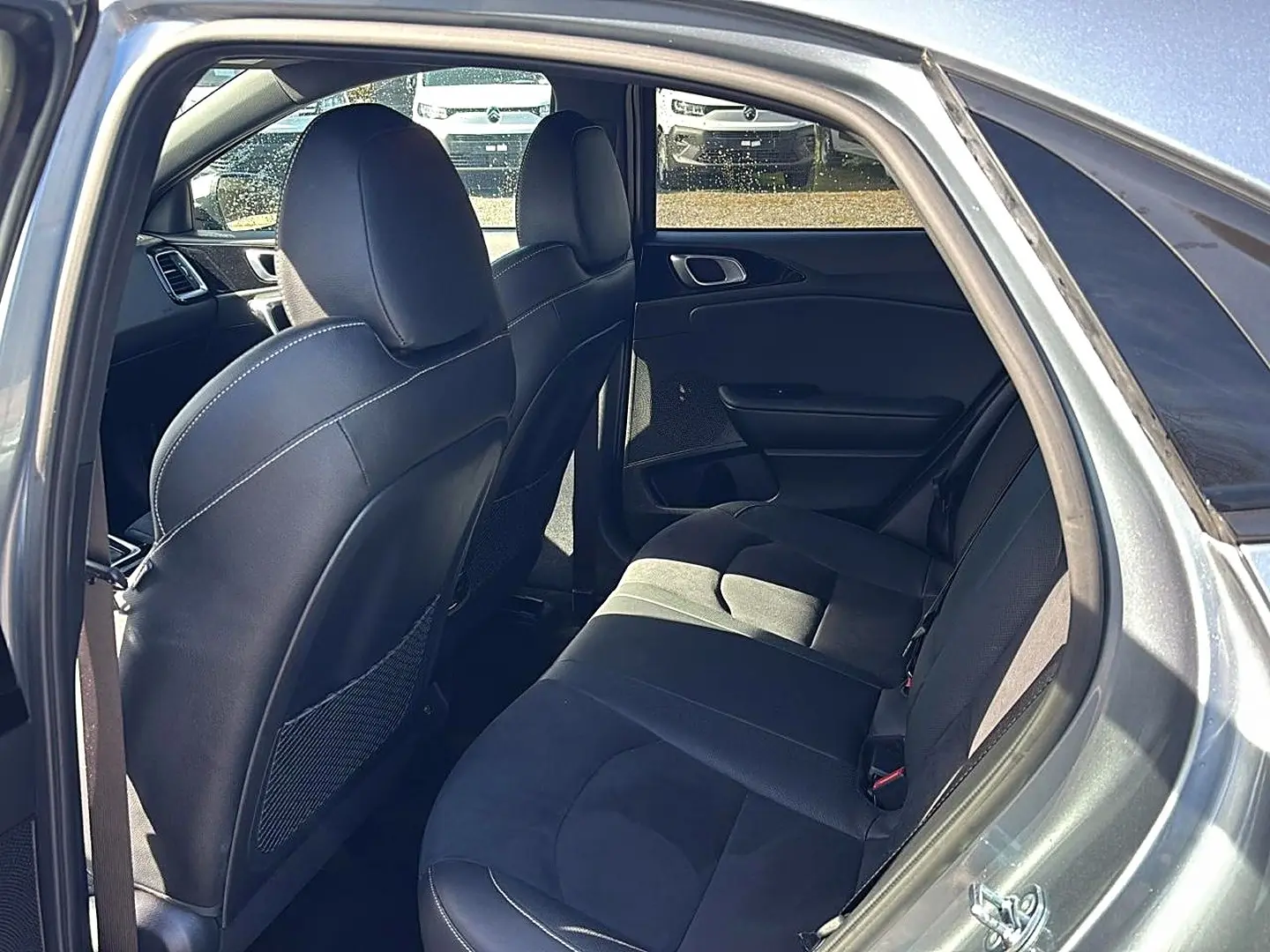 Vue intérieure arrière côté droit du Kia Xceed gris 2024, sièges en tissu noir avec appuie-têtes et rangements au dos des sièges avant.