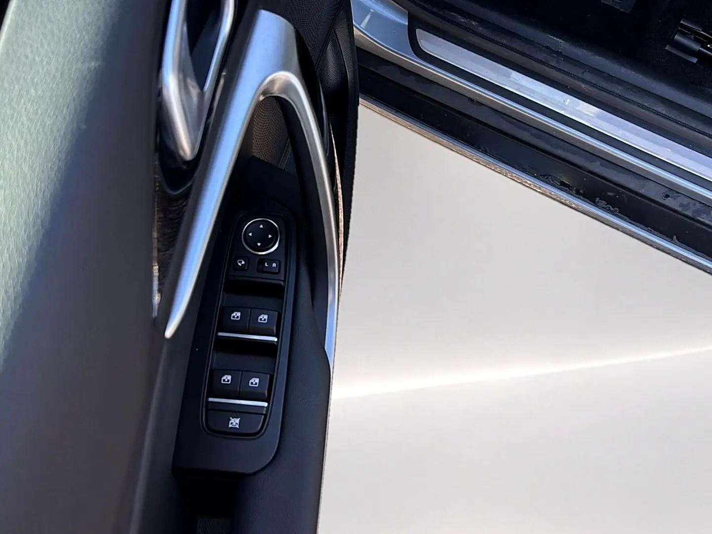 Détail de la porte côté gauche d’une KIA Xceed gris 2024, avec commandes électriques des vitres et rétroviseurs.
