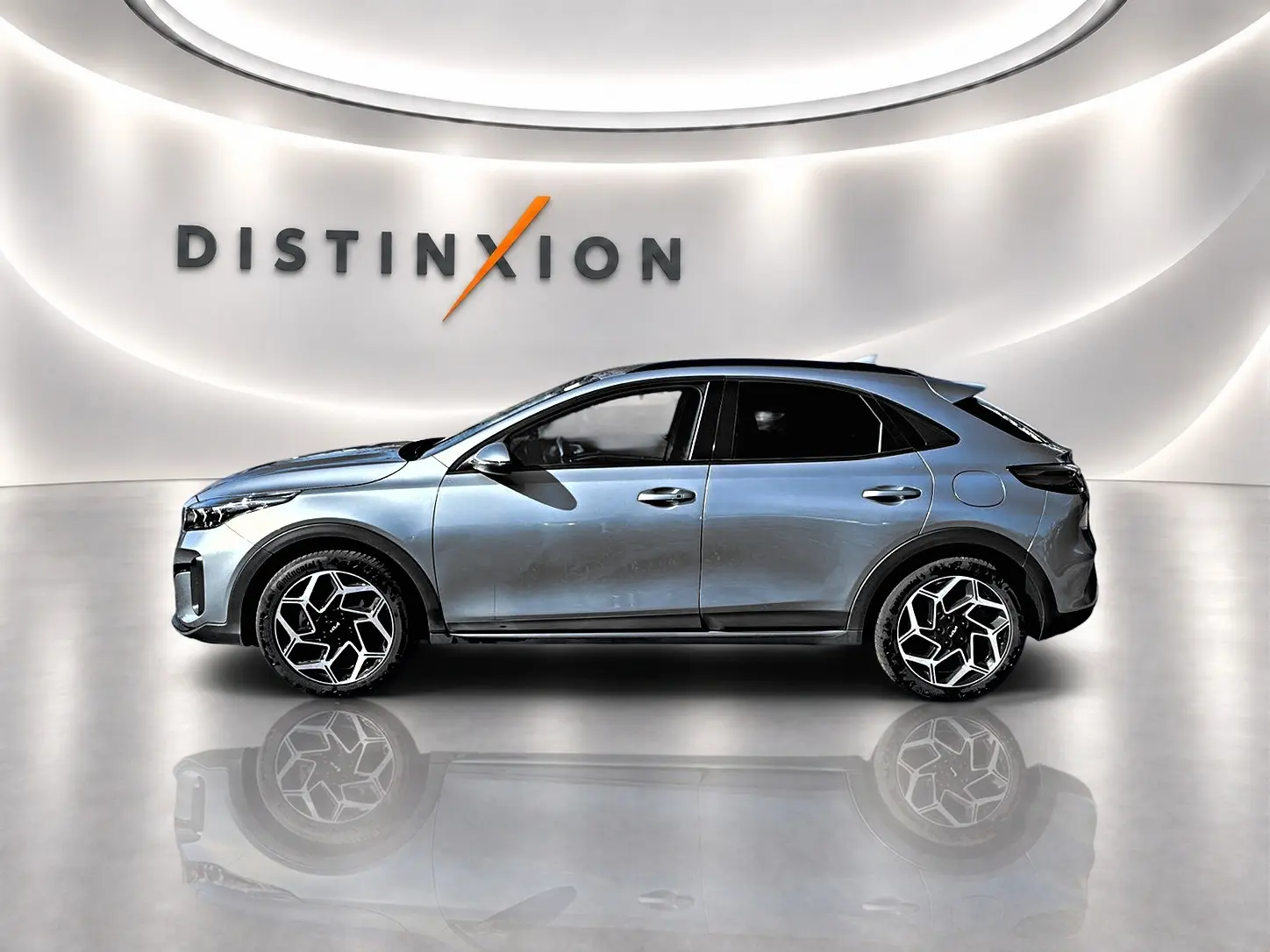 KIA Xceed gris en profil droit dans un showroom lumineux avec jantes alu au design hexagonal.
