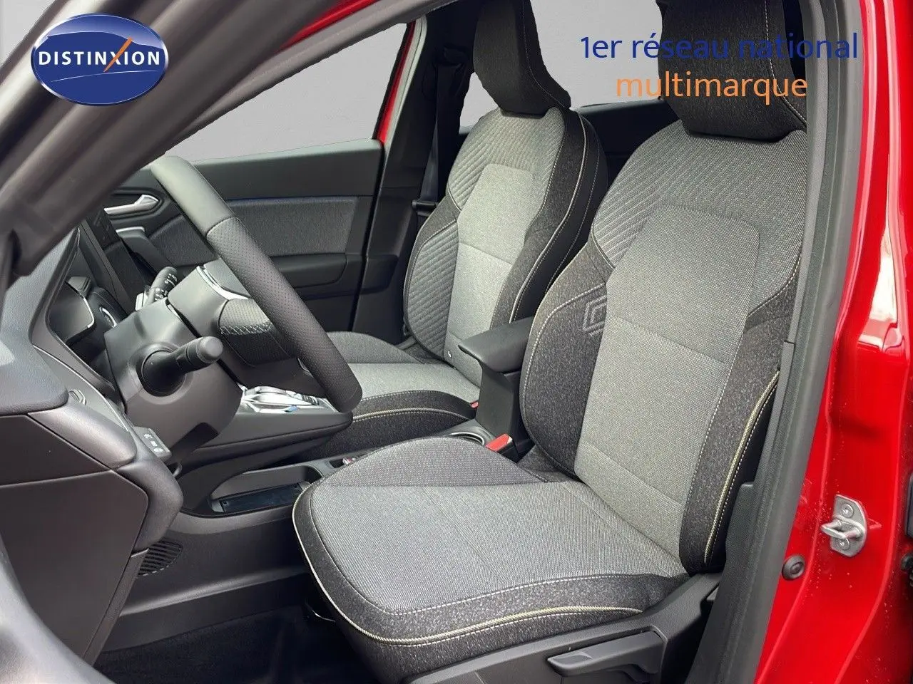 Intérieur avant du Renault Captur rouge passion, sièges tissu gris avec surpiqûres contrastées et volant visible.