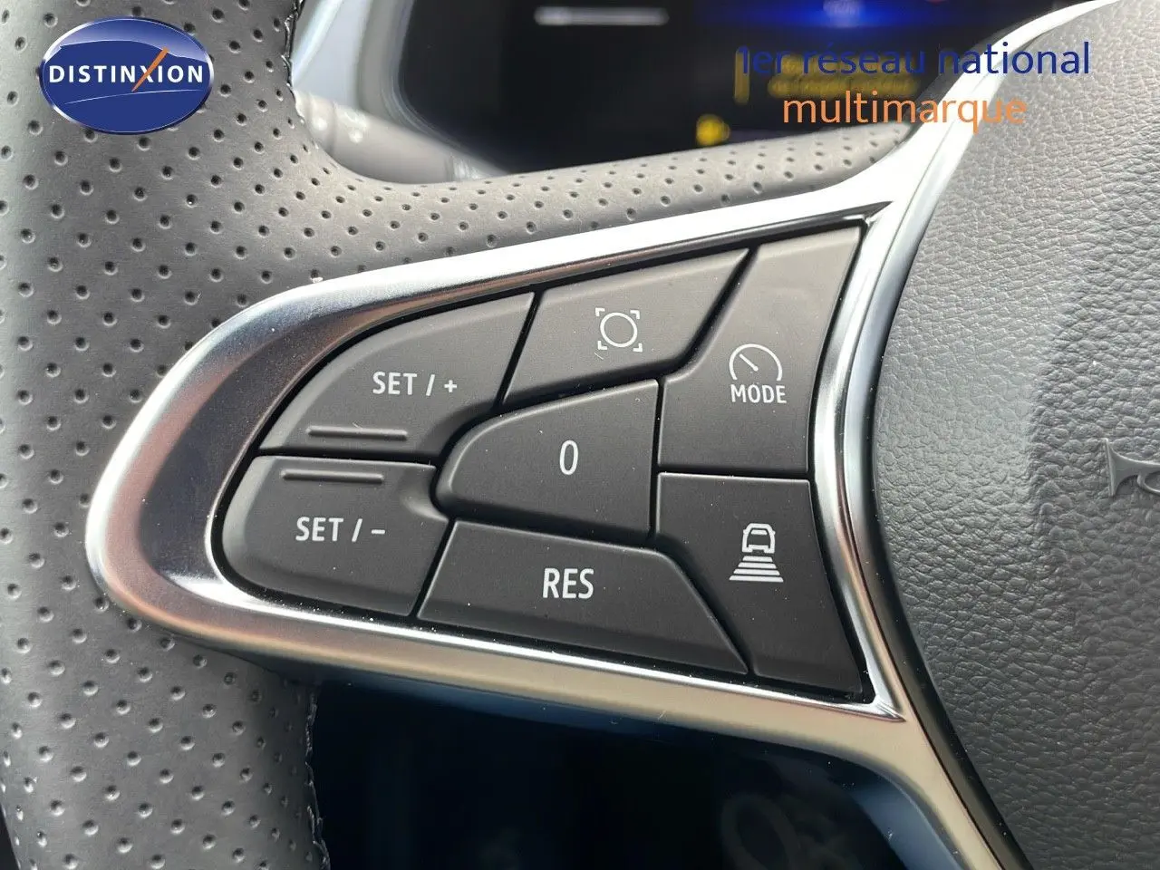 Gros plan sur les commandes de régulateur de vitesse au volant perforé du Renault Captur E-Tech hybride 2025.