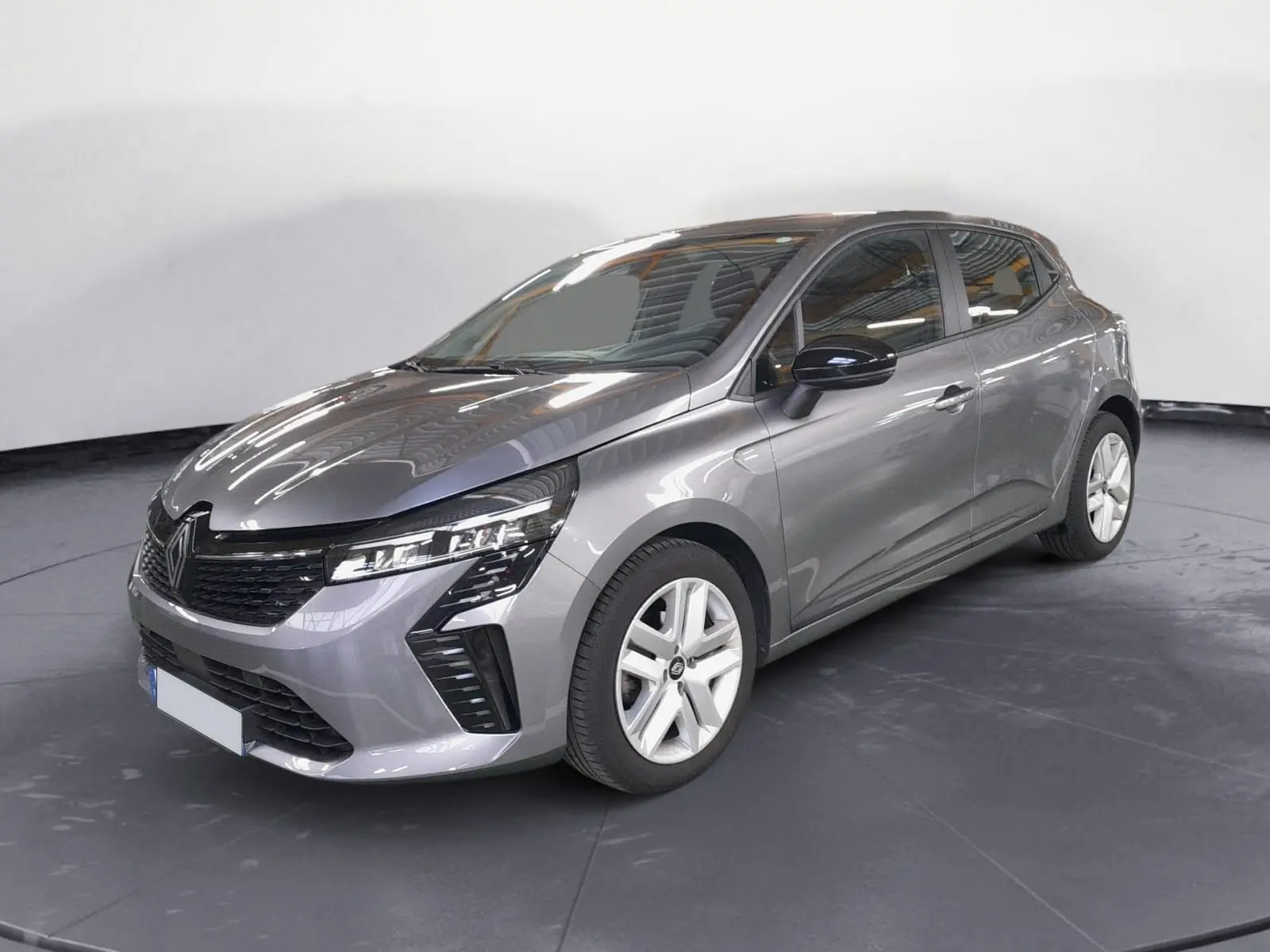 Renault Clio V gris schiste en 3/4 avant droit, avec phares LED et jantes alliage 16 pouces visibles.