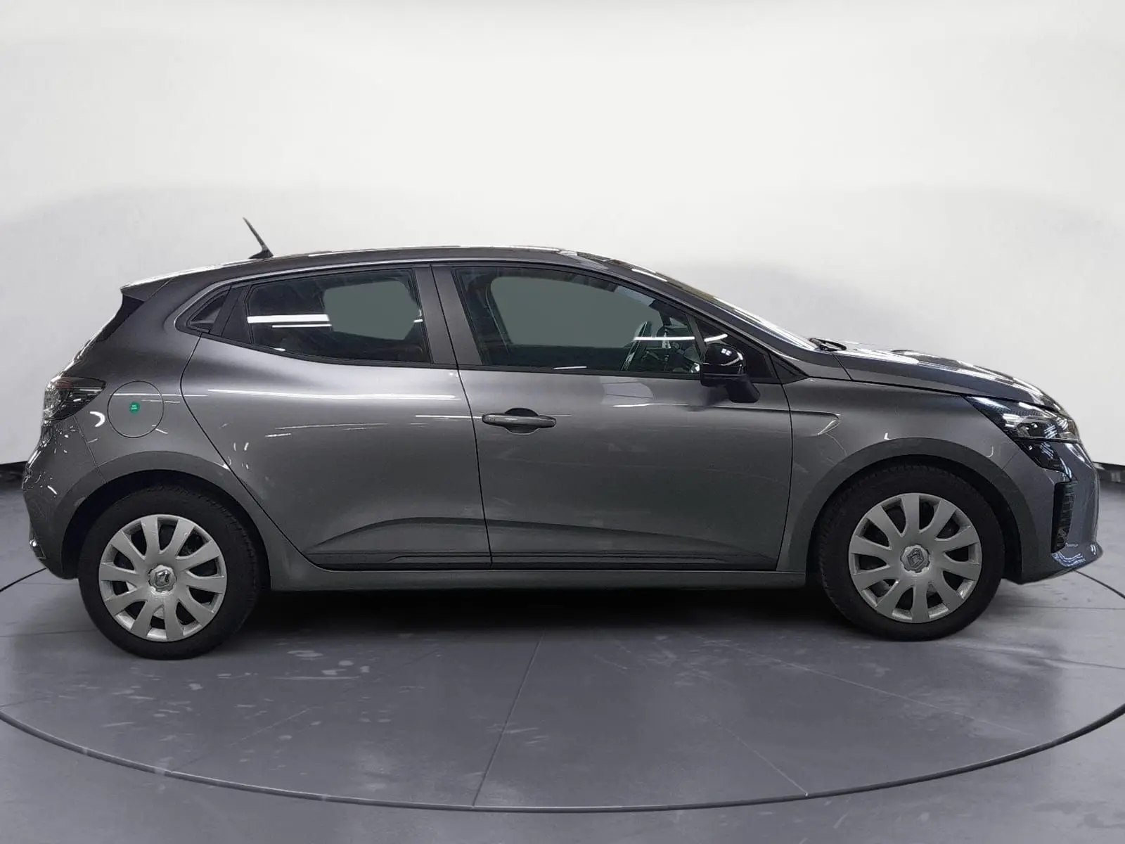 Profil droit d'une Renault Clio V gris schiste avec enjoliveurs 16 pouces, vue en intérieur studio neutre.