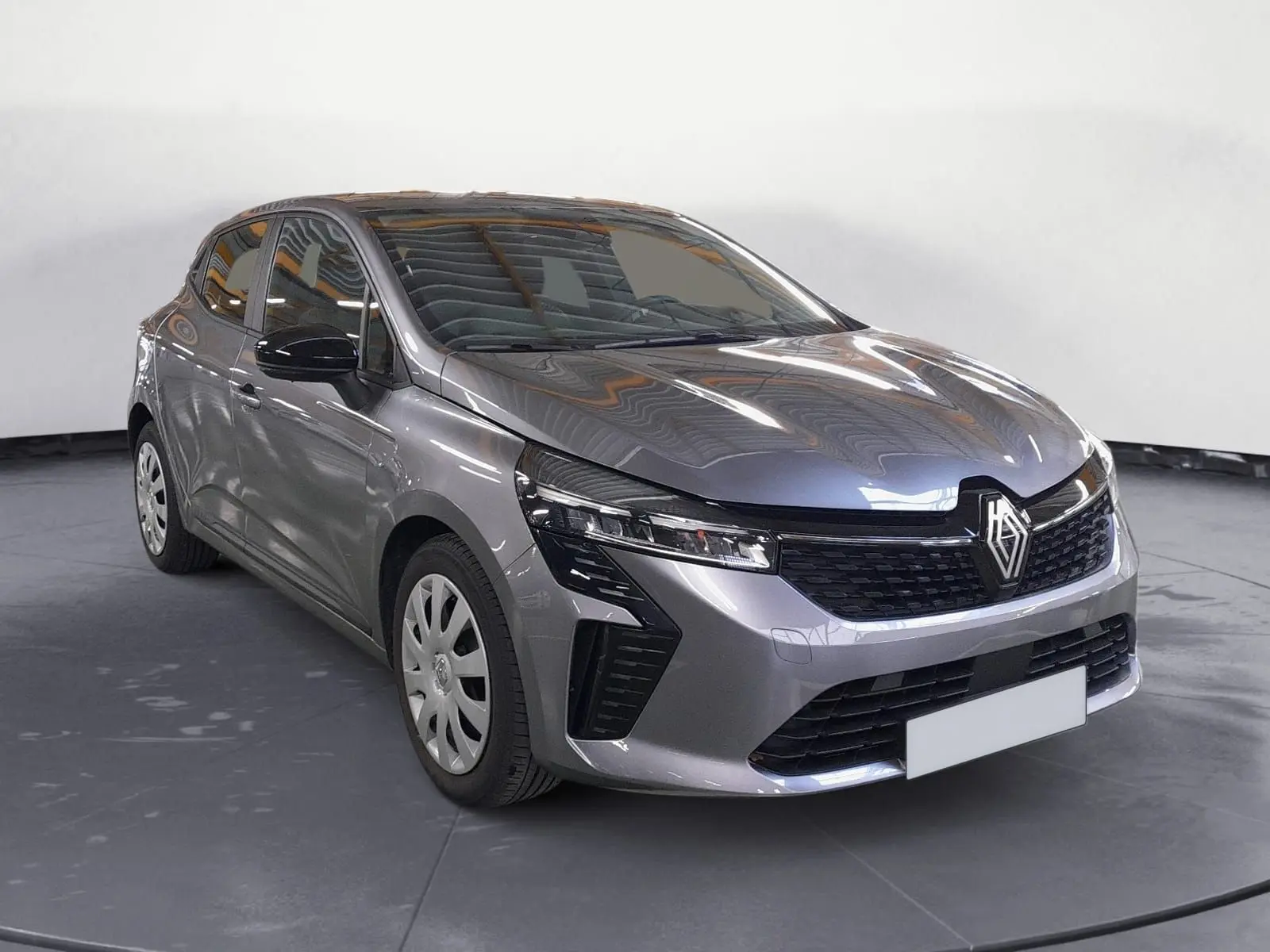 Renault Clio V gris schiste vue 3/4 avant avec enjoliveurs tôle 16 pouces et calandre noire distinctive.