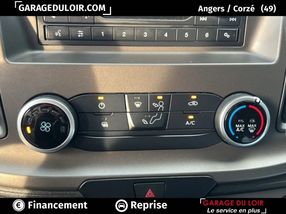 Gros plan sur les commandes de climatisation du Ford Transit Custom blanc, avec boutons et voyants allumés.