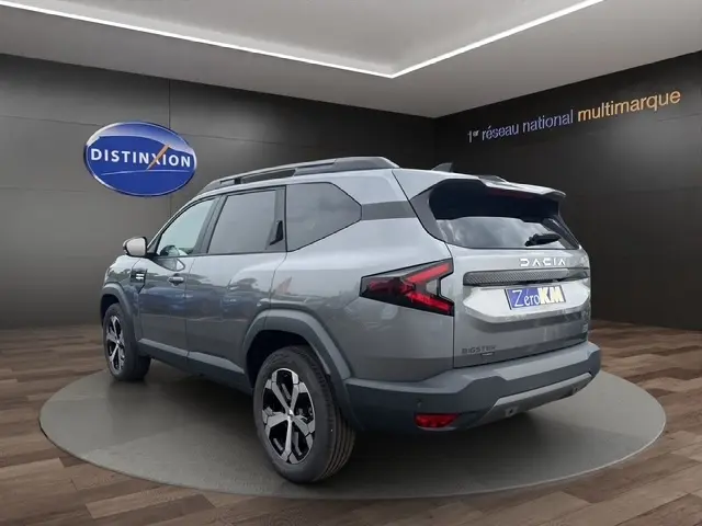 Vue 3/4 arrière droite d'un Dacia Bigster gris foncé avec feux arrière en forme de Z et jantes noires et argentées.