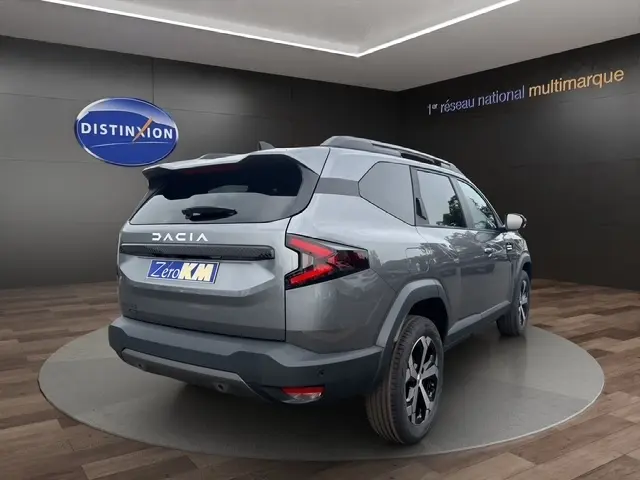 Vue 3/4 arrière droite du Dacia Bigster gris foncé avec feux arrière en forme de Z et jantes noires et argentées.