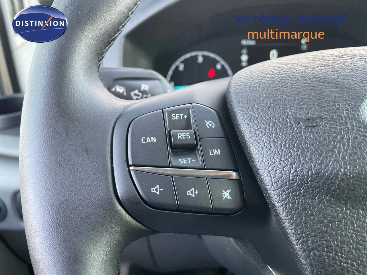 Gros plan sur les commandes du volant noir du Ford Transit Fourgon blanc, mettant en valeur les boutons de régulateur et audio.