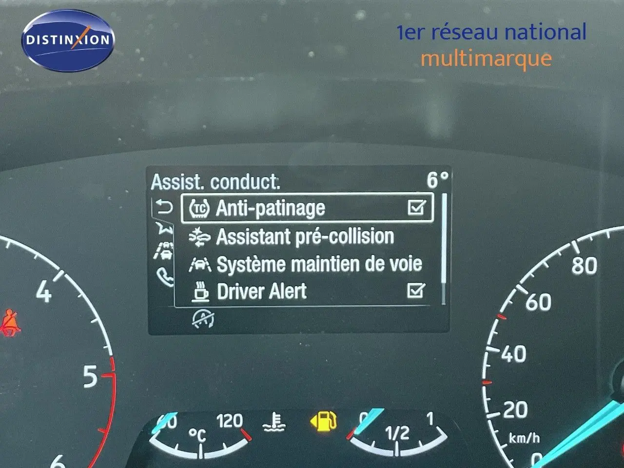 Tableau de bord du Ford Transit Fourgon blanc 2023 montrant l'écran d'assistance à la conduite et compteurs analogiques.