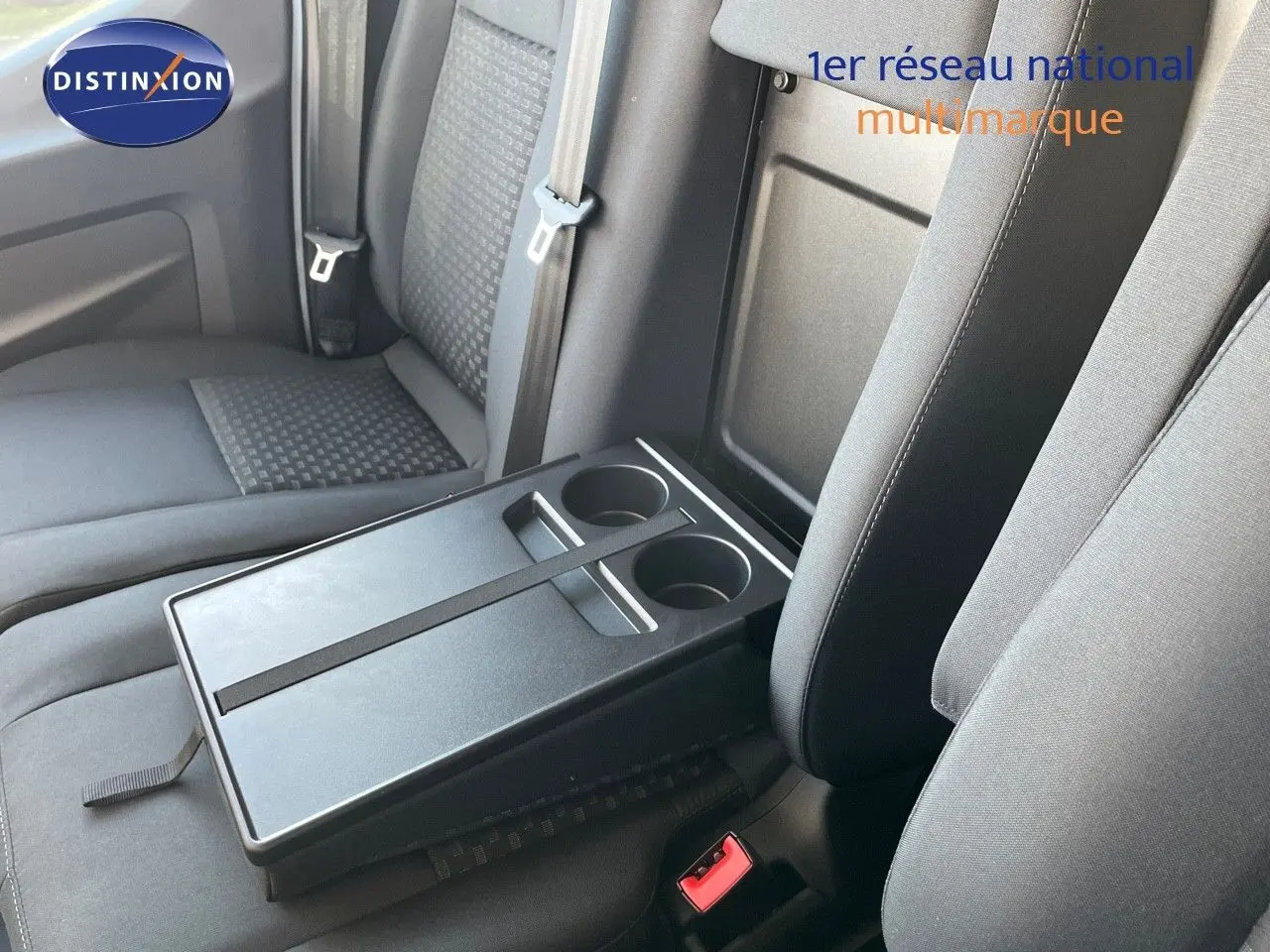 Détail intérieur montrant la banquette grise avec tablette rabattable et porte-gobelets du Ford Transit Fourgon blanc 2023.