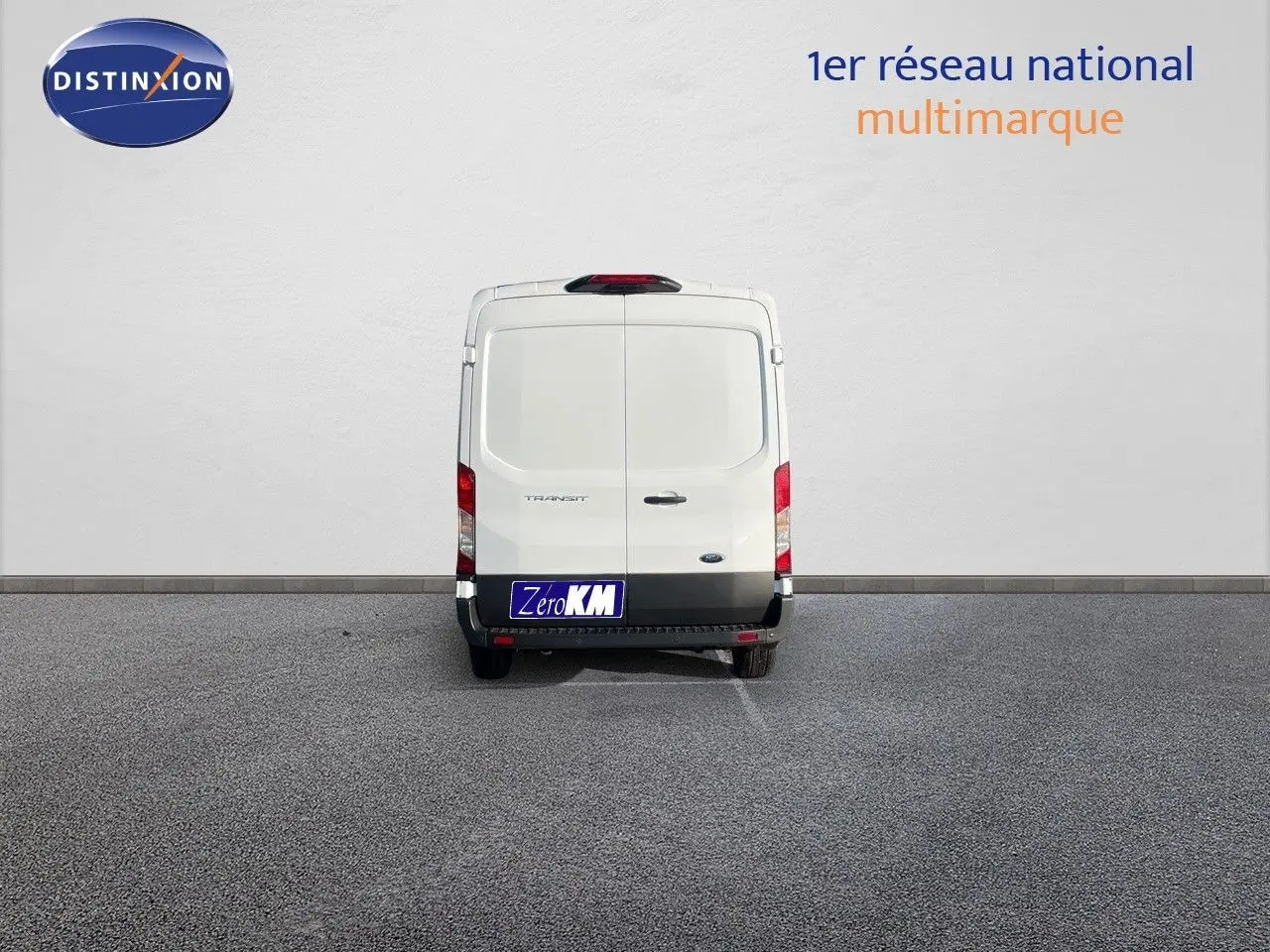 Vue arrière d'un fourgon Ford Transit blanc 2023 garé devant un mur blanc avec plaque Zero KM.