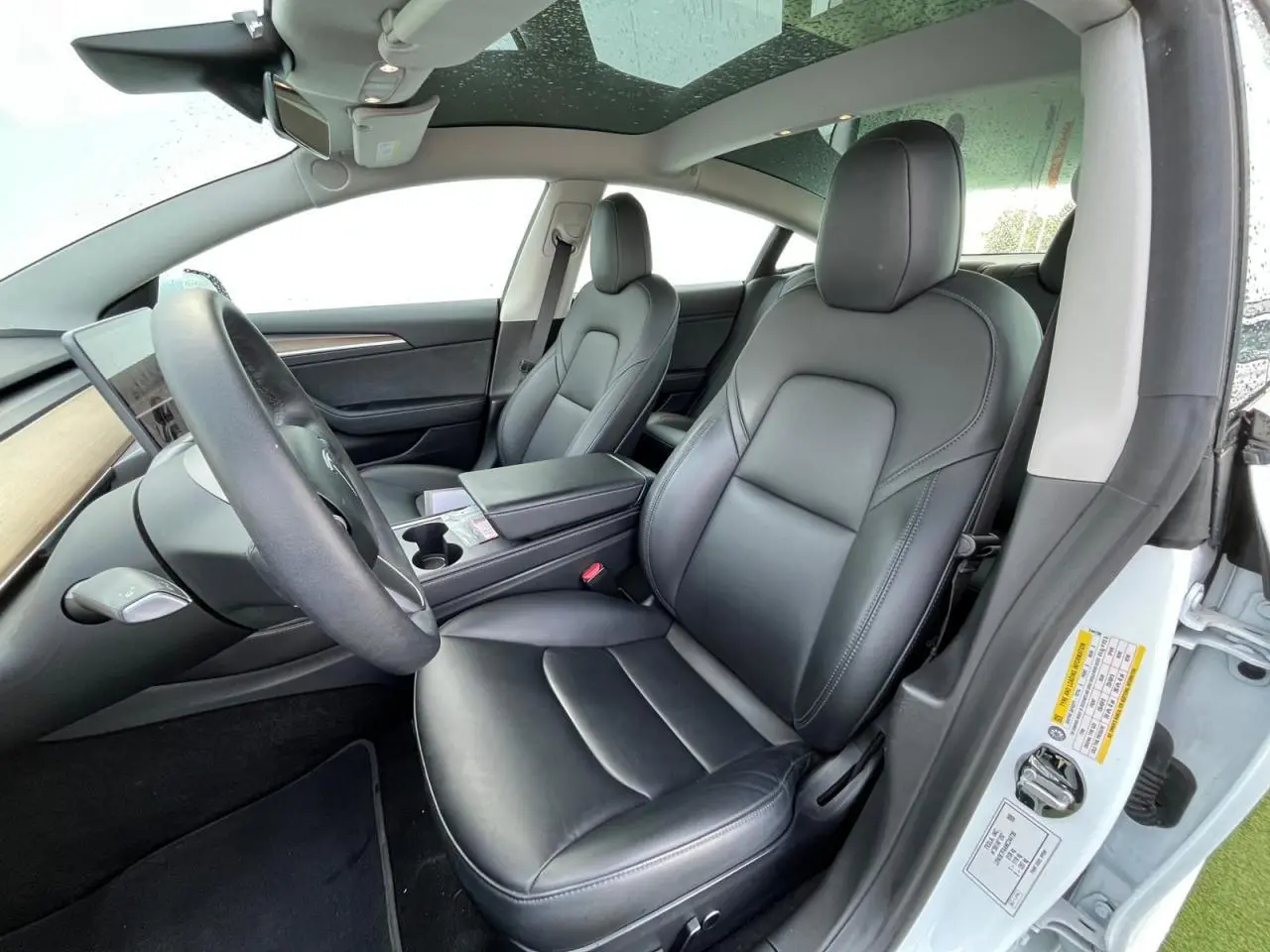 Intérieur noir premium de la Tesla Model 3 Standard Plus 2022, vue côté conducteur avec toit panoramique en verre.