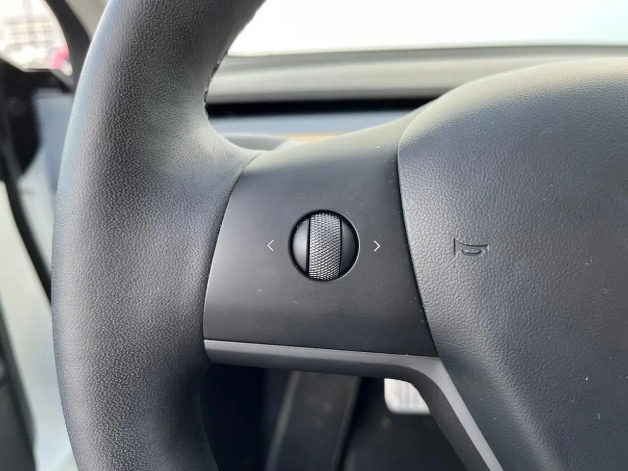 Gros plan sur la molette de commande gauche du volant noir d'une Tesla Model 3 Standard Plus RWD blanche de 2022.