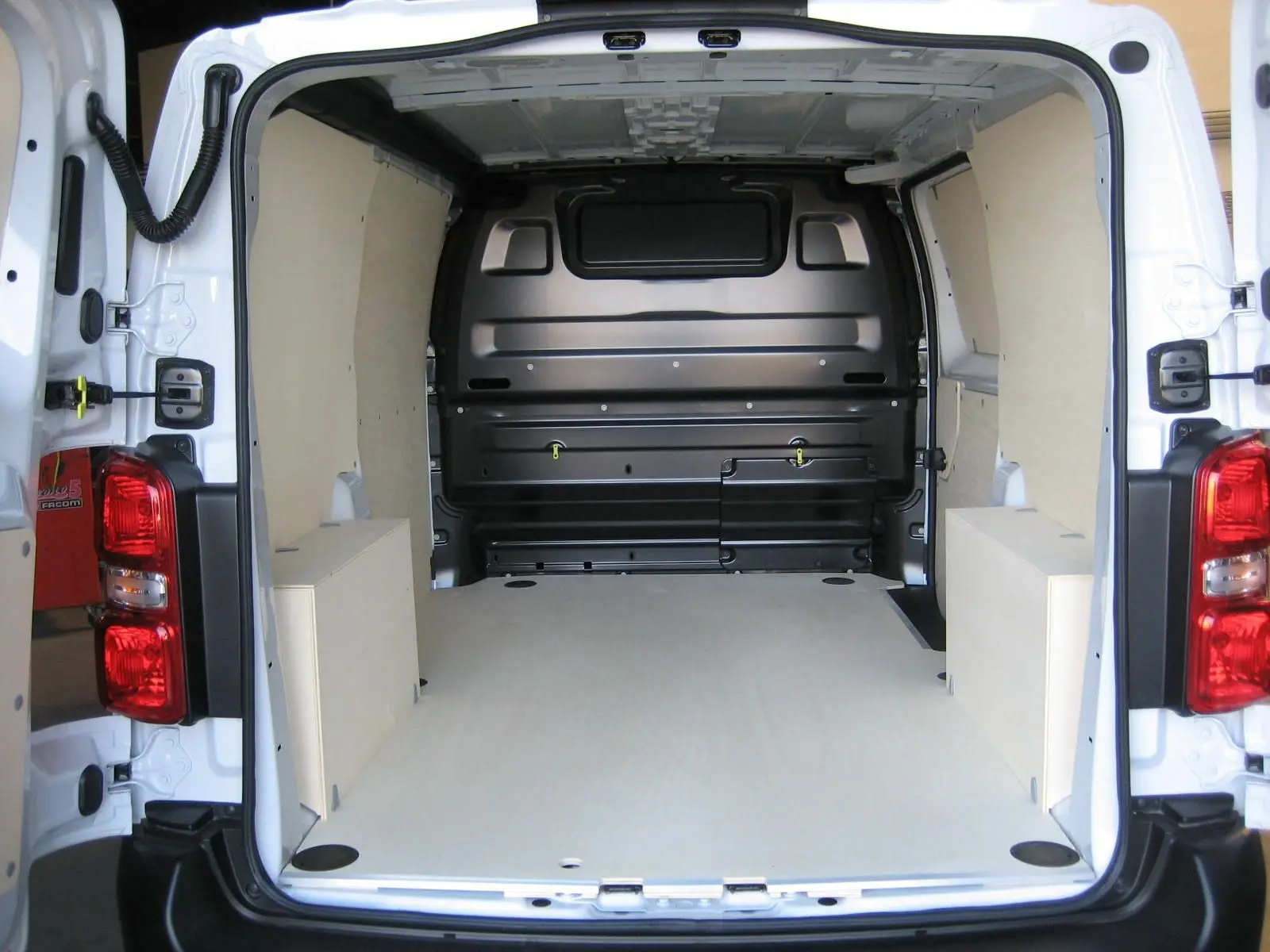 Vue arrière intérieure du Peugeot Expert Fourgon blanc 2025, montrant l'espace de chargement avec revêtement bois clair.