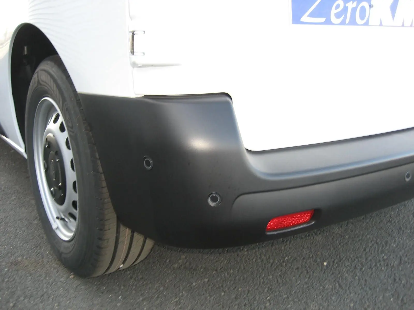 Gros plan sur le pare-chocs arrière noir et la roue côté gauche du Peugeot Expert Fourgon blanc 2025.