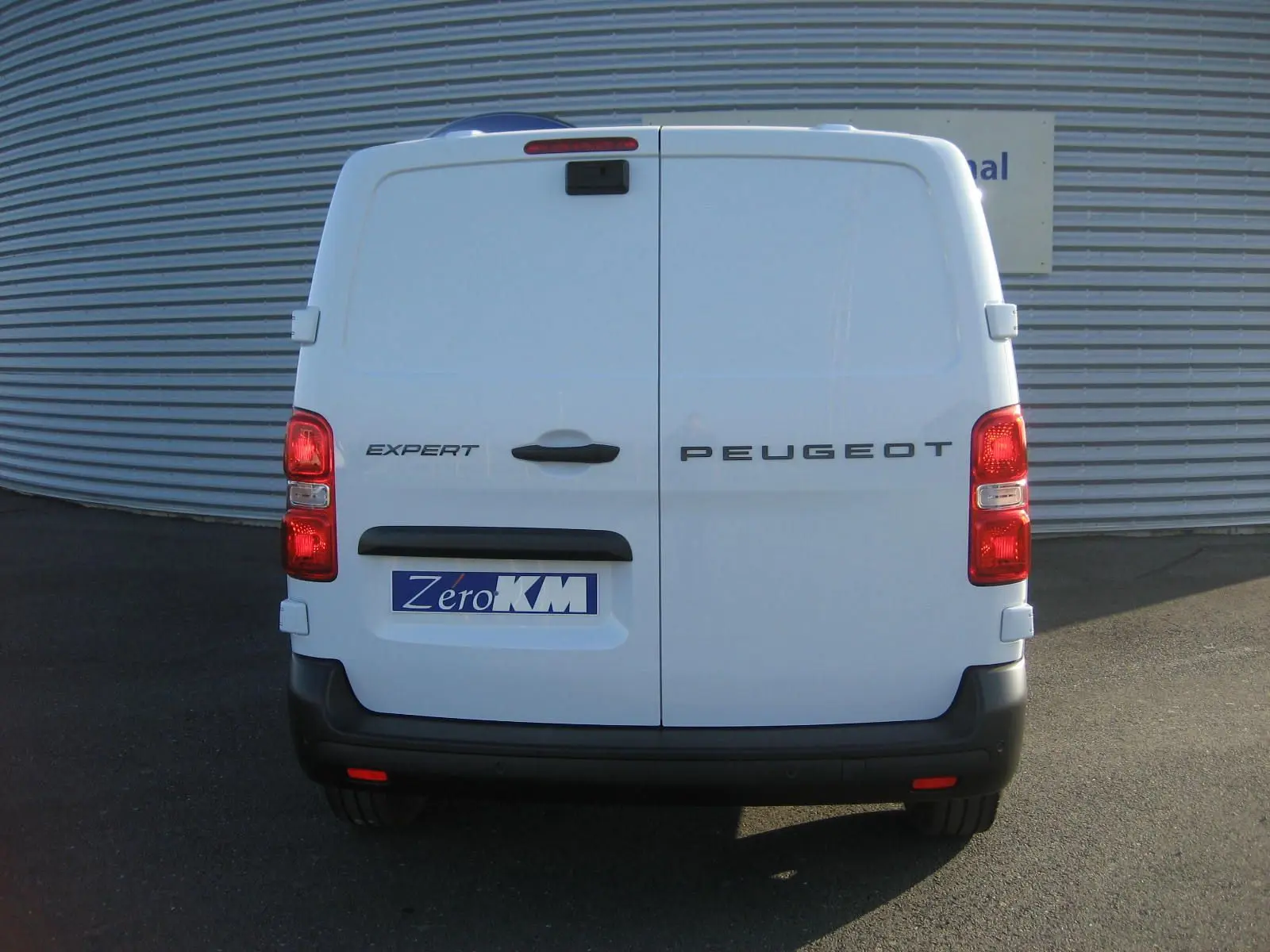 Vue arrière d'un Peugeot Expert Fourgon blanc 2025 avec portes battantes et feux rouges allumés.