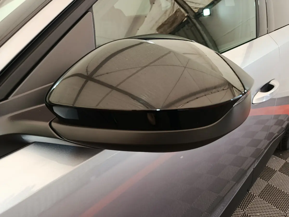 Rétroviseur droit noir brillant du Peugeot 3008 gris clair, vue rapprochée sur la portière avant.