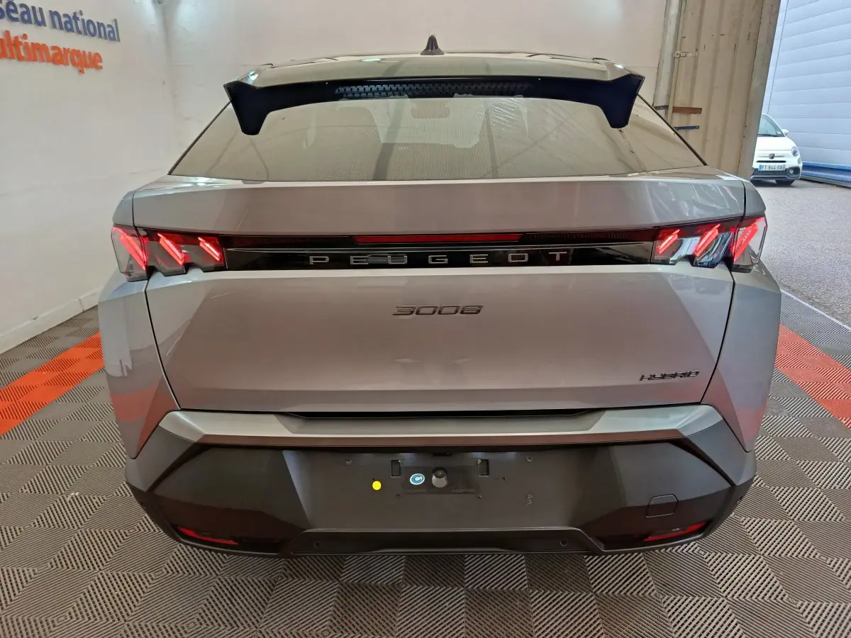 Vue arrière d'un Peugeot 3008 gris clair hybride avec feux LED distinctifs et logo central lumineux.