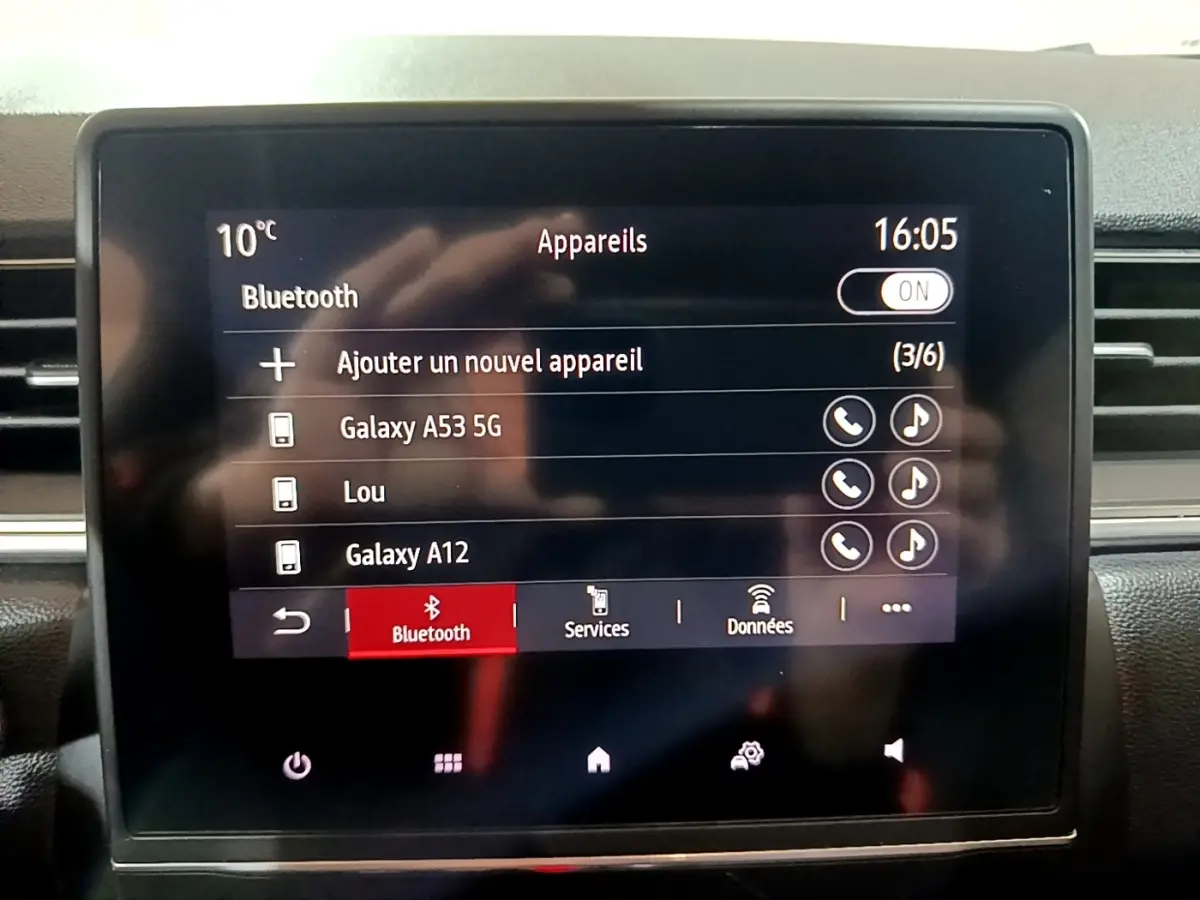 Écran tactile central du Renault Captur Intens jaune, affichant le menu Bluetooth avec plusieurs appareils connectés.