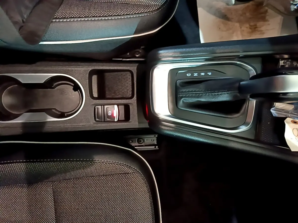 Vue plongeante sur la console centrale noire du Renault Captur Intens, avec levier de boîte auto et porte-gobelets.