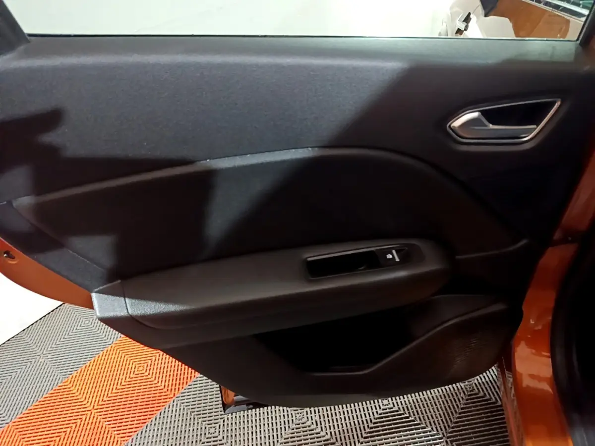 Vue intérieure du panneau de porte arrière droite du Renault Captur jaune, avec commande de vitre et poignée intégrée.