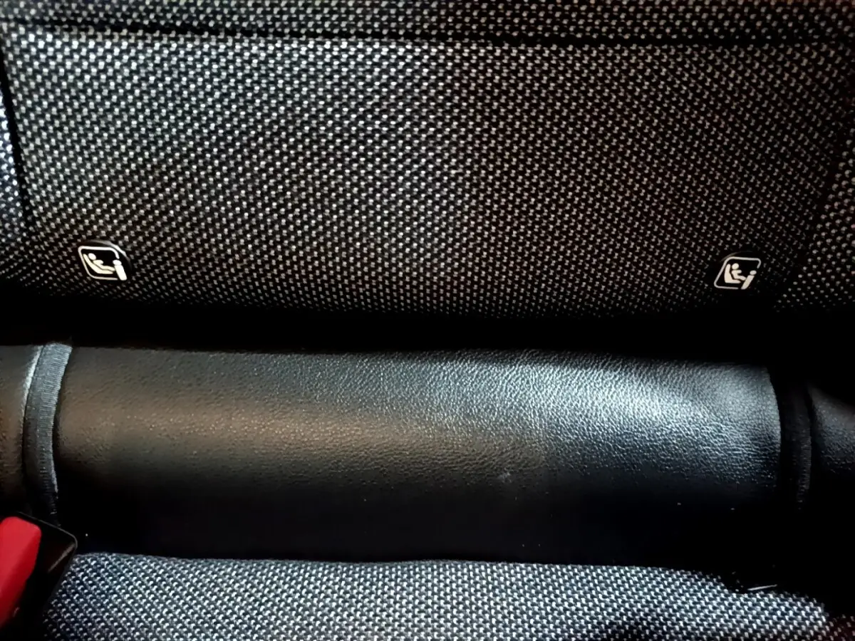 Gros plan sur la banquette arrière noire du Renault Captur Intens, montrant les fixations Isofix et la ceinture rouge.