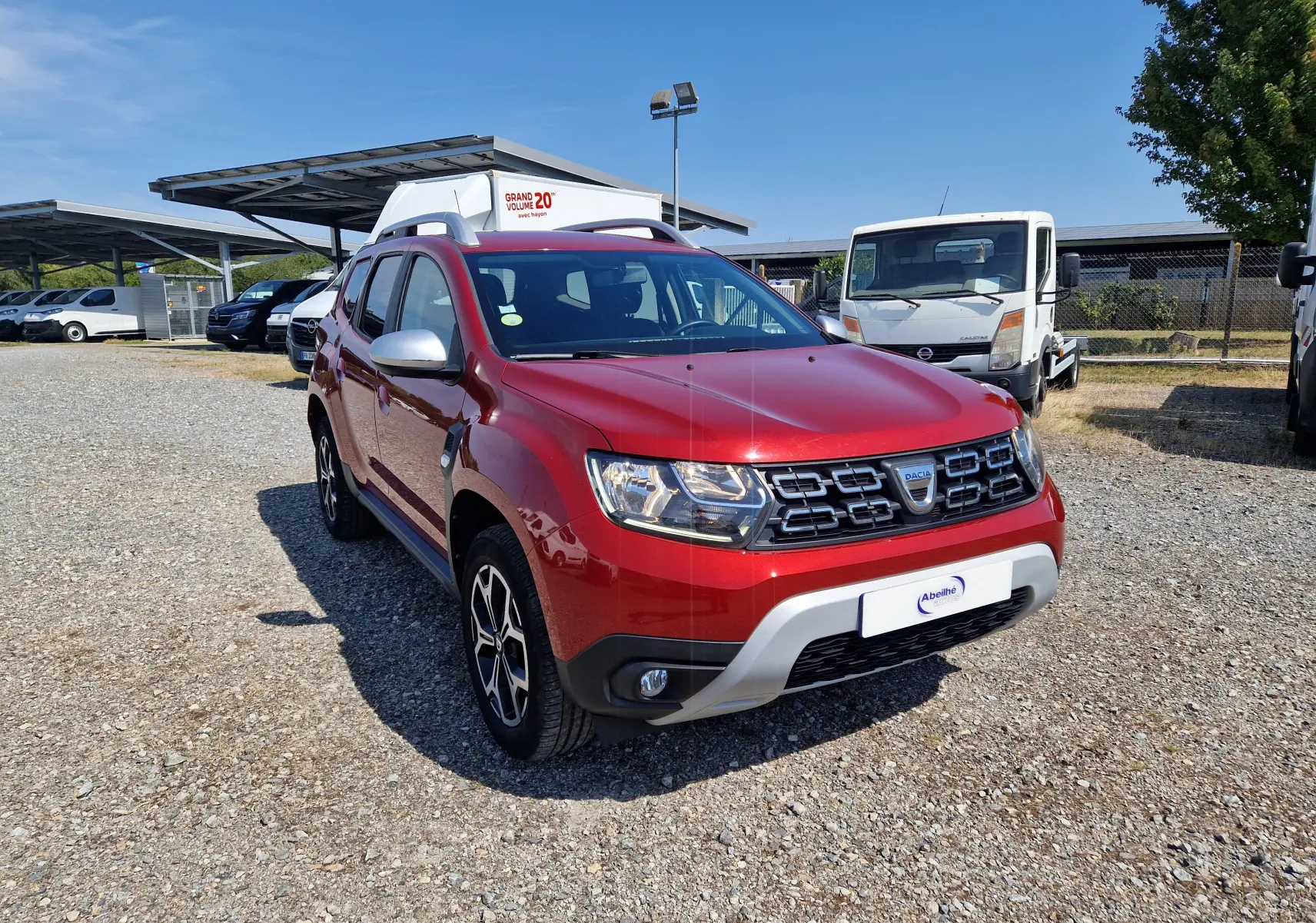 Dacia Duster rouge fusion en 3/4 avant droit, avec calandre noire et jantes alliage noires et argent.