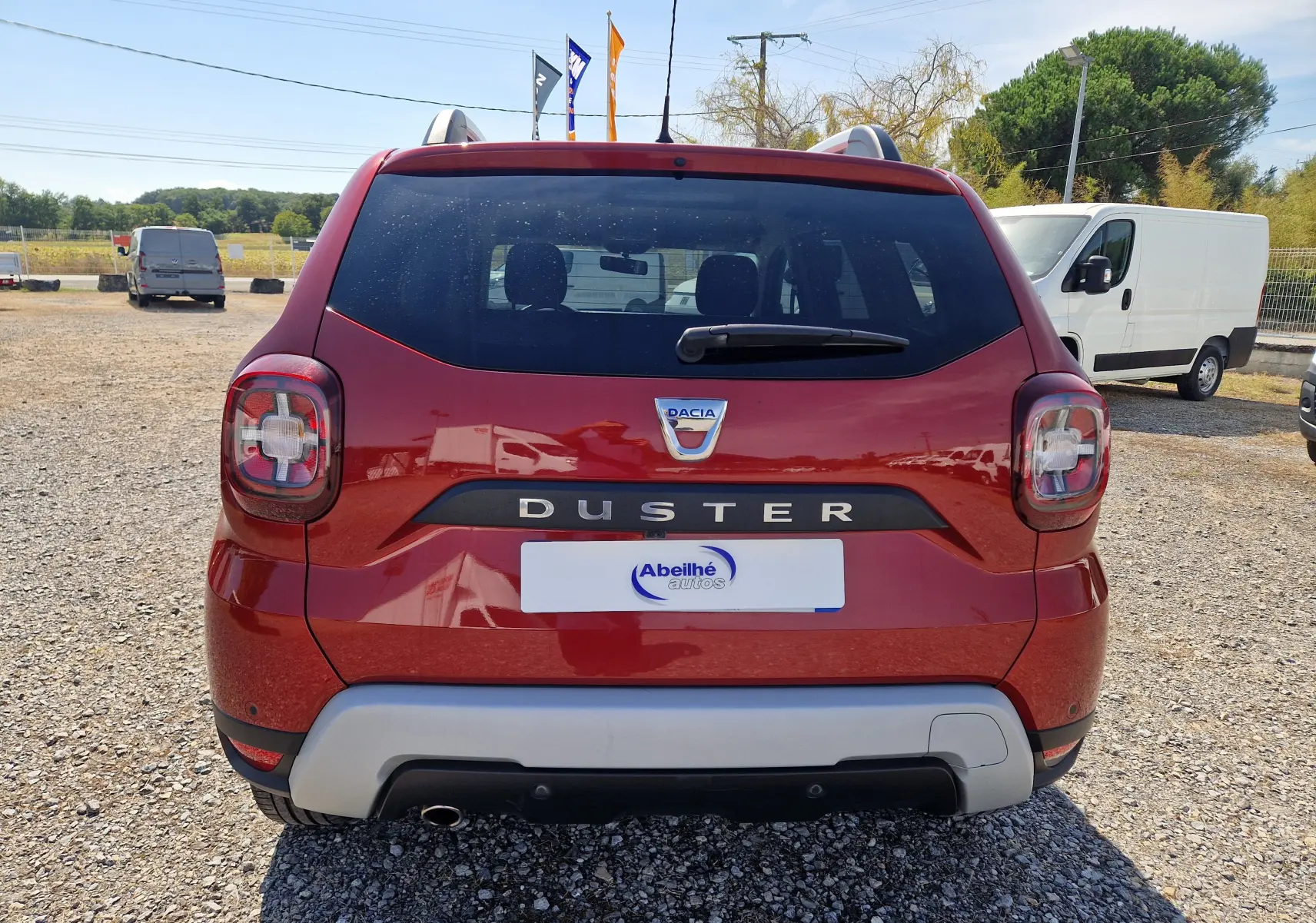 Vue arrière d'un Dacia Duster rouge fusion 2021 avec feux arrière caractéristiques et logo central visible.