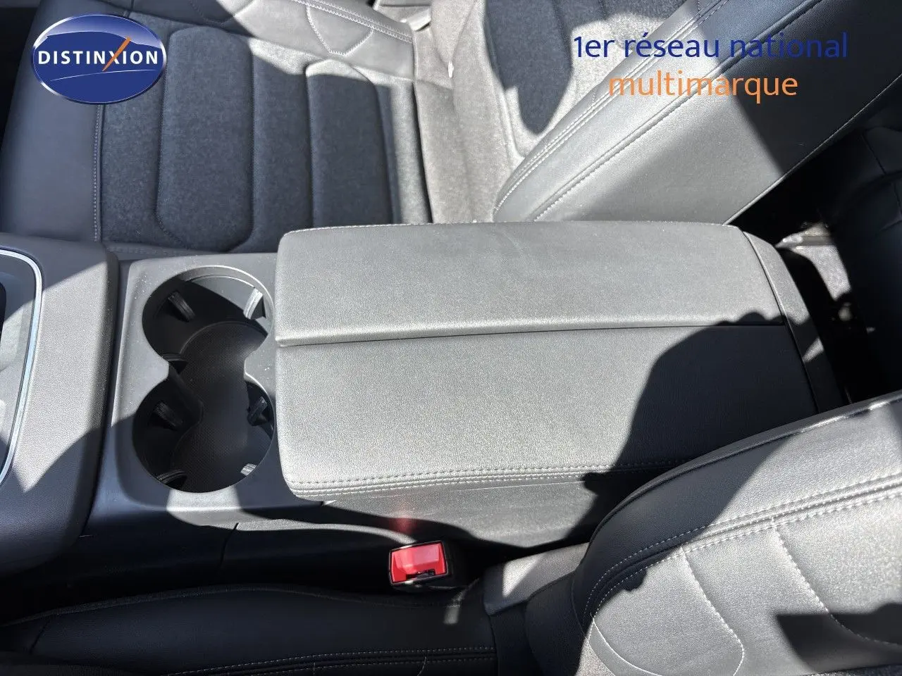 Détail de l'accoudoir central et porte-gobelets en cuir noir à l'avant intérieur du Citroën C5 Aircross 2025.