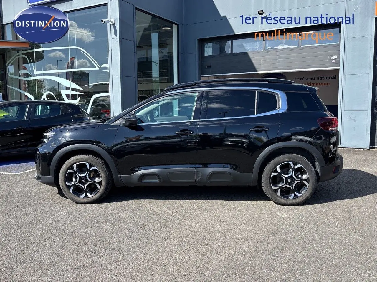 Vue de profil côté gauche d'un Citroën C5 Aircross noir Perla Nera métallisé, avec jantes distinctives et protections latérales.