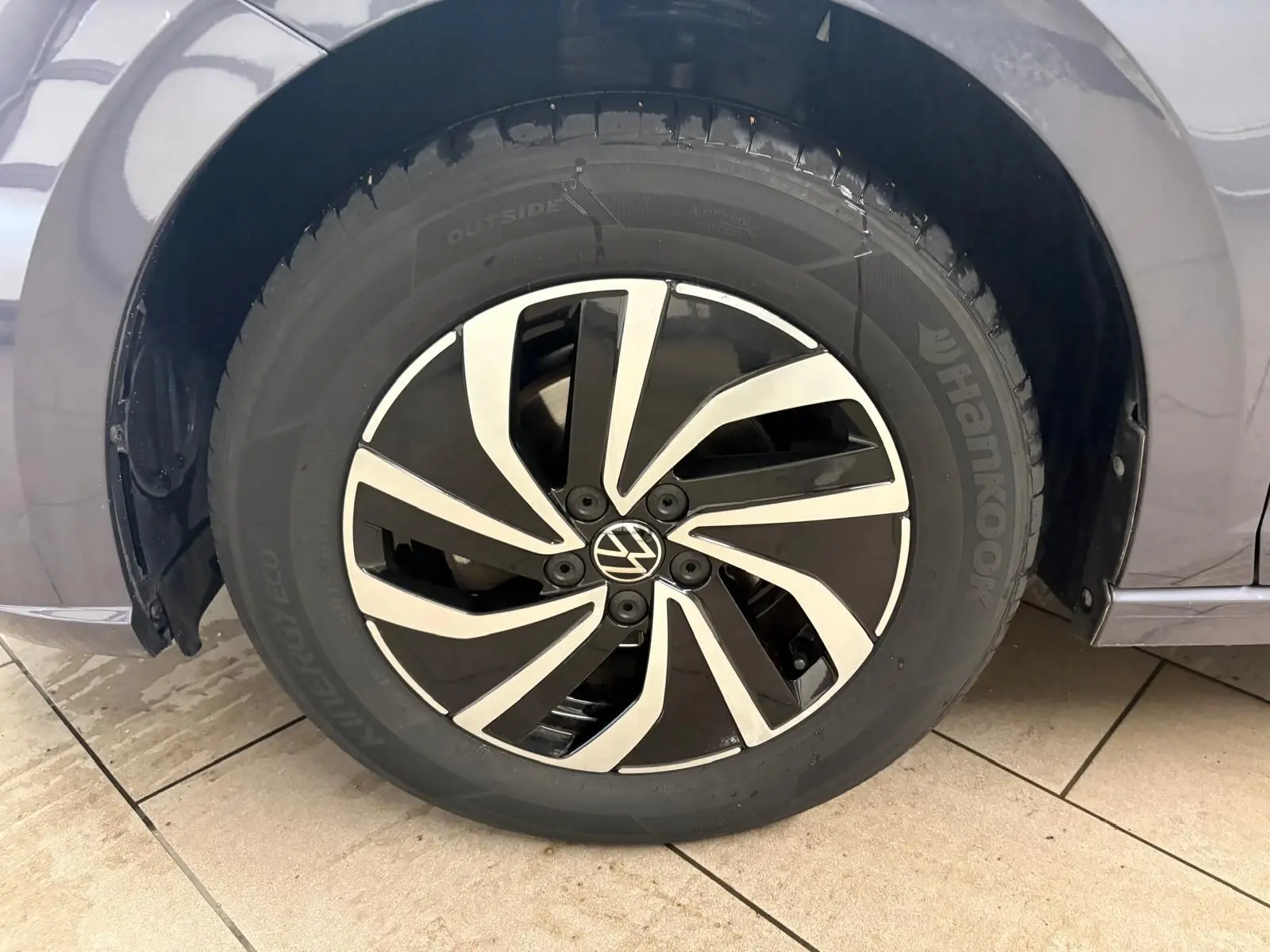 Gros plan sur la roue avant gauche d’une Volkswagen Polo gris cendre 2024 avec jante alliage noire et argent.