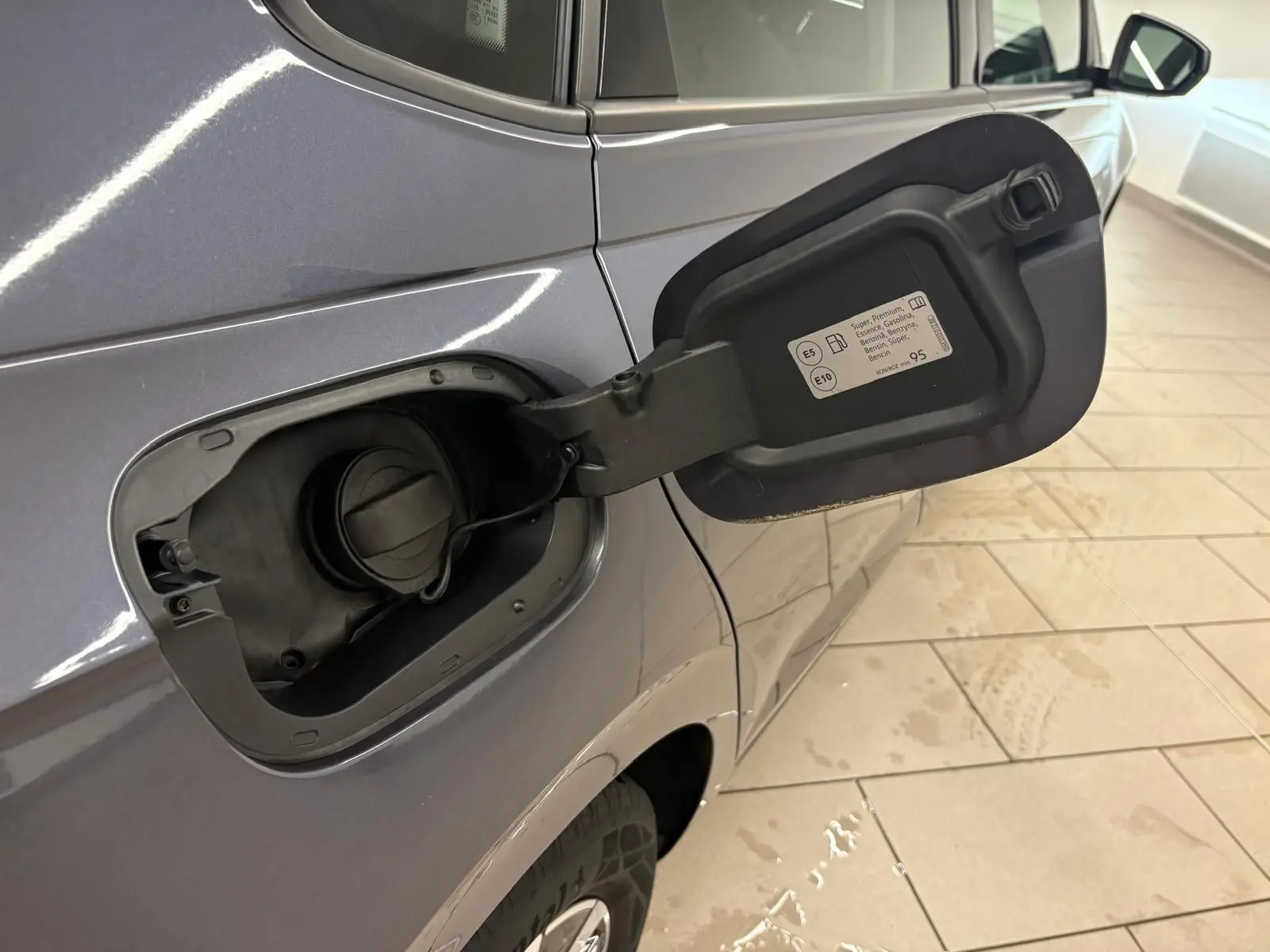 Vue rapprochée du côté gauche arrière d’une Volkswagen Polo gris cendre 2024 avec trappe à carburant ouverte.