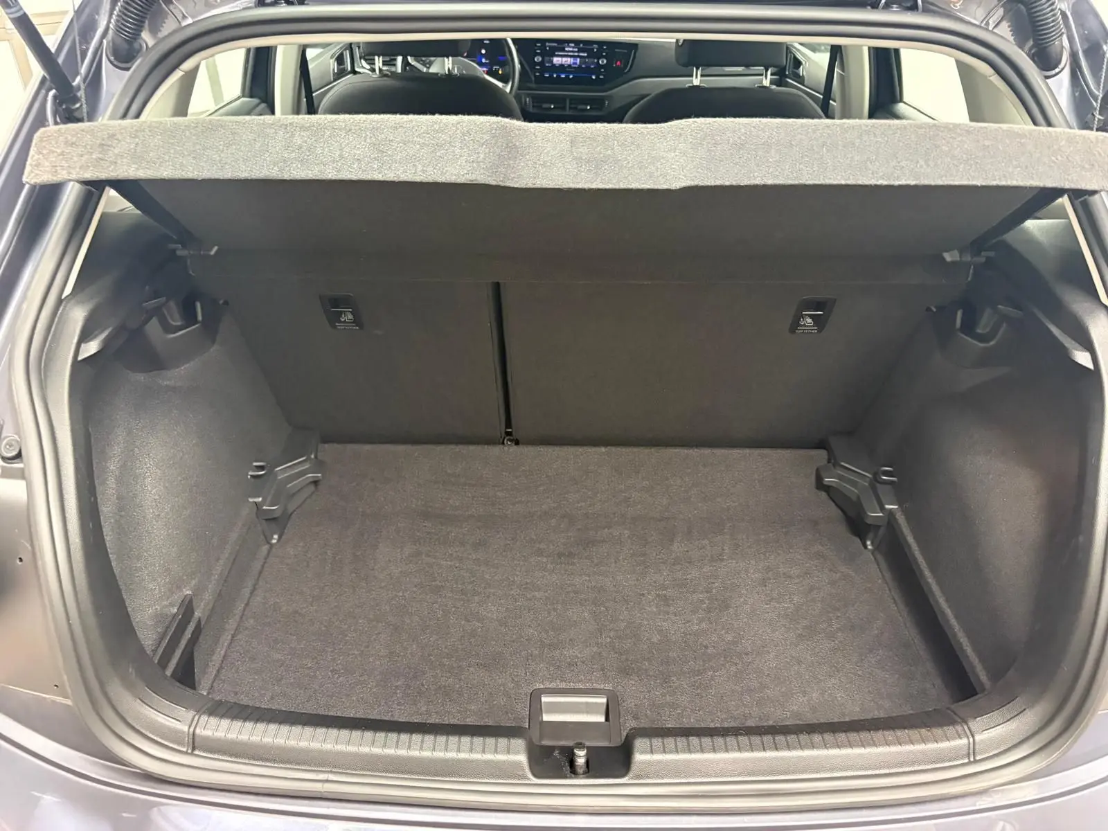 Coffre ouvert d’une Volkswagen Polo gris cendre 2024, vue arrière montrant l’espace de chargement et l’intérieur du véhicule.
